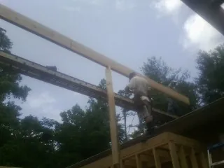 Carpenter setting a ridge beam over a new addition frame — Ice Dam Removal by Roofing Brothers in Whitestone