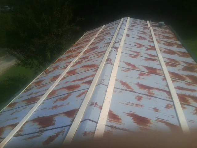 Rusted metal roof panels with new wood purlins before replacement — Storm Damage Roof Repair in Whitestone by Roofing Brothers