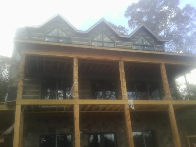 Dormers and porch framing on a large log home under construction — Roof Coating work by our crew in Whitestone