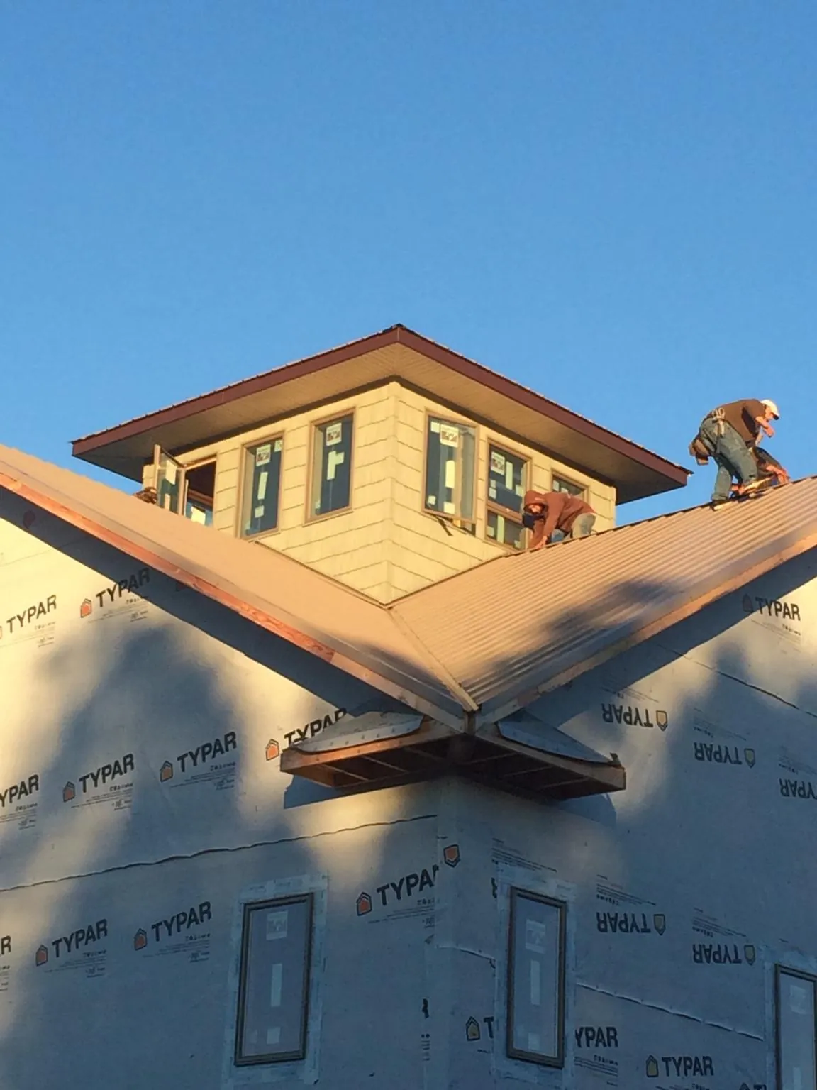 Roofers working around a rooftop cupola on a new metal roof at sunset — Roof Waterproofing in Whitestone by Roofing Brothers